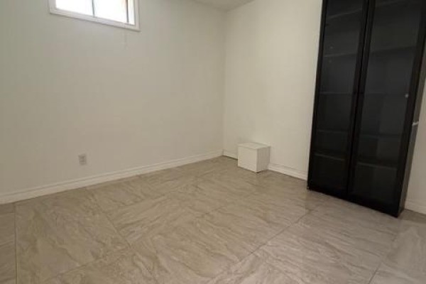 Empty basement room with white walls, window, tiled floor and black cabinet. - (basement) - 366 Waratah Avenue, Newmarket