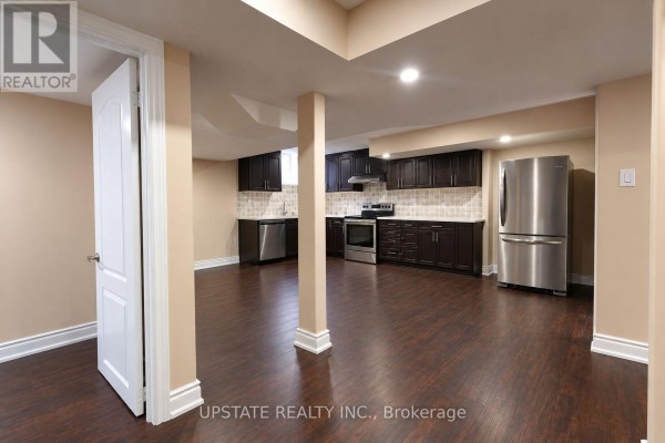 Open concept basement living area with a dark wood kitchen and dark wood floors. - (basement) - 8 Sage Meadow Crescent, Brampton