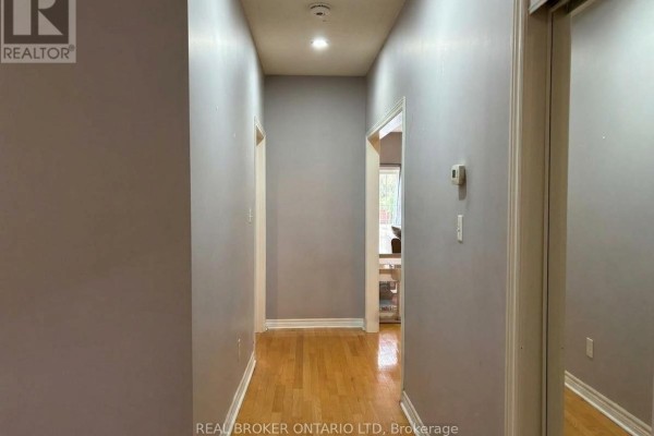 Interior hallway with light grey walls and light oak hardwood floors, leading to doorways. - (main) - 88 Sir Jacobs Crescent, Brampton