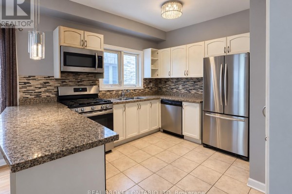 Kitchen with white cabinetry, granite countertops, stainless steel appliances, and tiled backsplash and floor. - (main) - 88 Sir Jacobs Crescent, Brampton