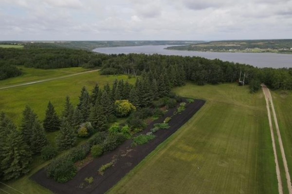 Aerial view of a garden bed and treed area next to a gravel road with a river in the distance. - , Lake Of The Prairies