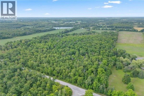 Aerial view of a large forested property bordered by a paved road and green fields. - . Fourth Line Nassagaweya, Milton