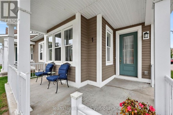 Close-up of a townhouse porch with two blue chairs, a green front door, and decorative flowers. - 0 - 1 Samantha Lane, Midland
