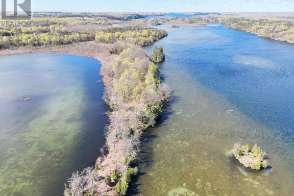 Aerial view looking down a peninsula of trees bordering a clear, shallow lake. - 0 Applewood Lane, Frontenac
