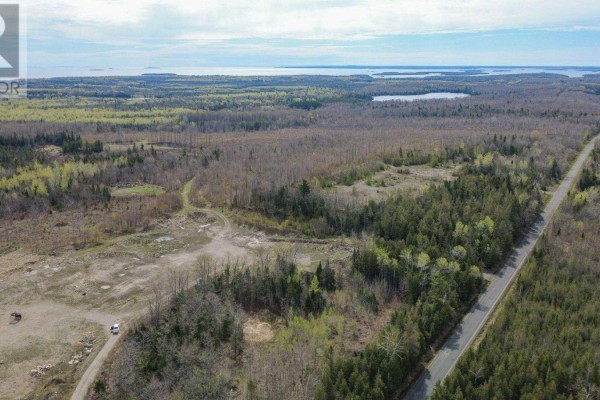 Overhead view of undeveloped land with rough terrain, scattered trees, and a dirt access road. - 0 Base Line Rd, Hilton Beach