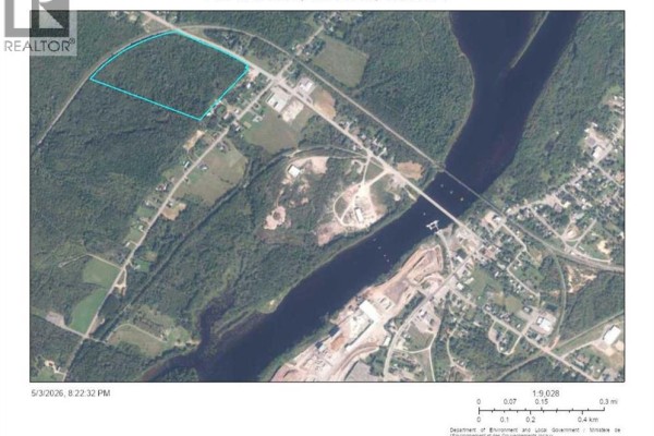 Aerial view of wooded land parcel outlined in blue, across from a wide river with a bridge. - 0 Bridge St Street, Chipman