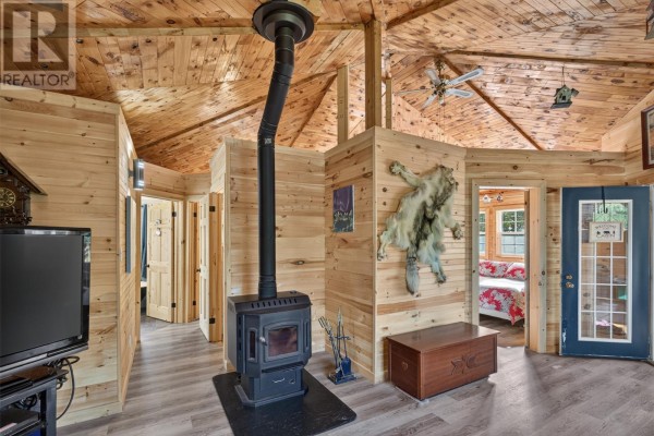 Living area with wood paneling, a wood stove, and doors leading to other rooms. - 0 Dam Pond Road, Brigus Junction
