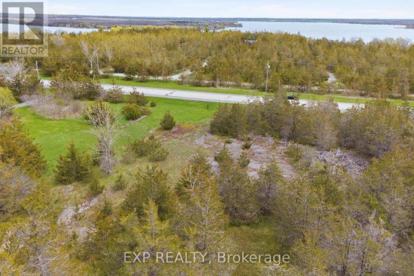 Aerial view showing a wooded parcel with houses and fields adjacent to a highway. - 0 Highway 49 Highway W, Prince Edward County