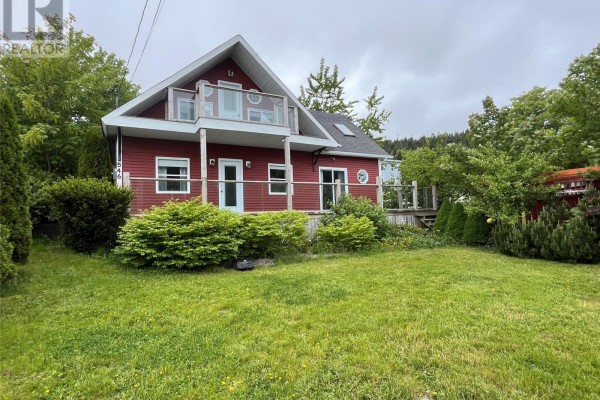 Red house exterior with a deck and mature trees, viewed from the side. - 0 Main Road, Bauline East