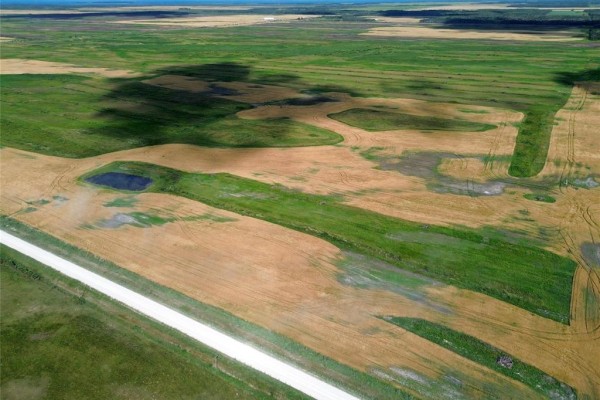 Wide aerial shot of a large farm field with a road and scattered trees. - 0 Moore Dale Road, Ste Rose Du Lac
