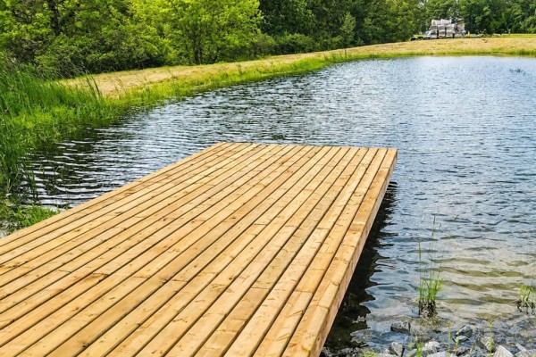 A wooden deck extends from a grassy bank into a calm pond with rippling water. - 0 Old Bog Road, Lorette