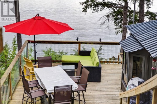 Wooden deck with outdoor furniture, red umbrella, and a view of the water. - 0 Panache Lake, Espanola