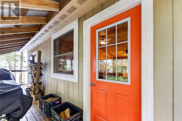 Exterior view of an orange door with glass panes and windows on a covered porch. - 0 Panache Lake, Espanola