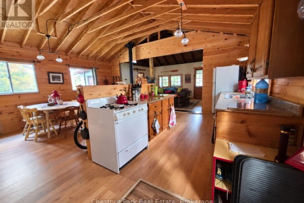 View of a rustic kitchen and dining area with wood-paneled walls and vaulted ceiling. - 0 Rock Lake Road, Algonquin Highlands