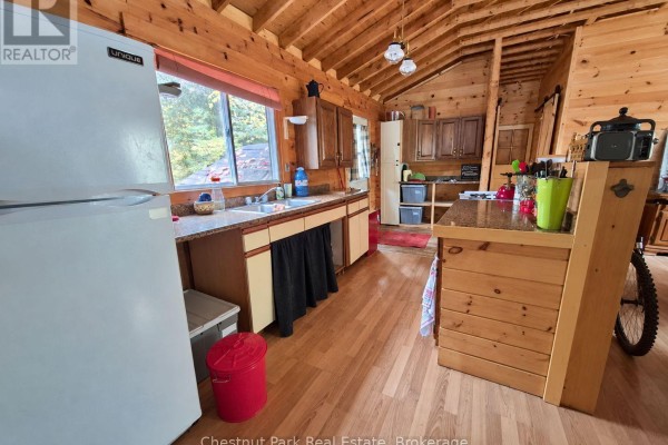 Kitchen interior with white refrigerator, speckled countertops, wooden cabinets, and sink. - 0 Rock Lake Road, Algonquin Highlands