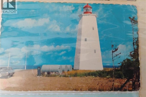 Tall white lighthouse with a red top on a rocky shore with blue sky. - 0 Ward/miscou Road, Miscou