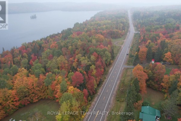 Aerial view of a highway bordering a lake and forest during peak autumn foliage season. - 00 62 Highway, Hastings Highlands