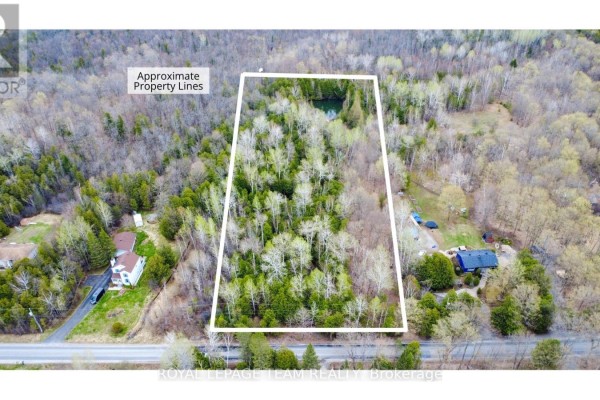 Drone view over dense forest with a small pond and yellow kayak visible in the distance. - 00 Bolton Road, North Grenville