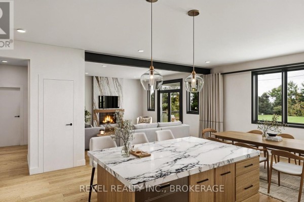 Open concept kitchen and living area, featuring a marble island, dining table, and fireplace view. - 00 Manitou Crescent, Loyalist