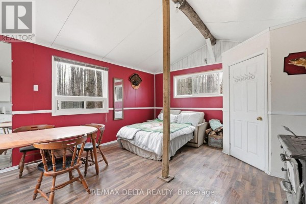 Interior of a small cabin showing a bed, dining table, wood stove, and red walls. - 00 Part Of Lot 11 Gagne Road, Clarence Rockland