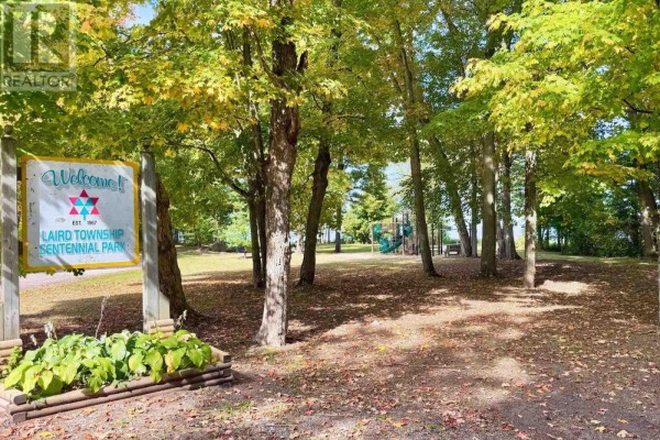 Park entrance sign welcoming visitors to Laird Township Centennial Park, with playground equipment visible. - 000 Pumpkin Point Rd E, Laird