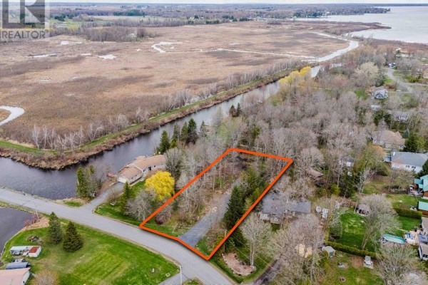 Aerial view of a treed lot outlined in orange, with a canal on the left and houses on the right. - 0000 Tree Haven Road, South Glengarry