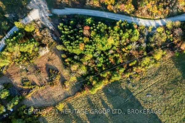 Aerial view shows a treed property with a gravel road and surrounding landscape. - 00000 Hideaway Lane, Frontenac