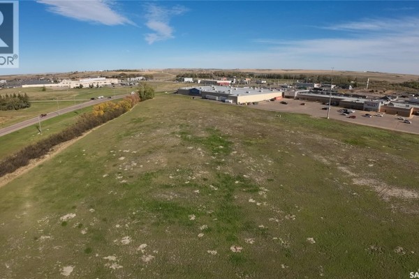 Aerial view of a green field adjacent to a road and a commercial building. - 01 Springs Drive, Swift Current