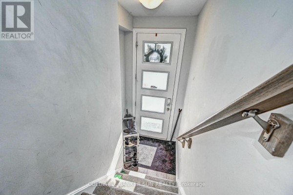 View looking down from the top of a staircase towards the front entrance and shoe rack. - 03 - 314 Equestrian Way, Cambridge