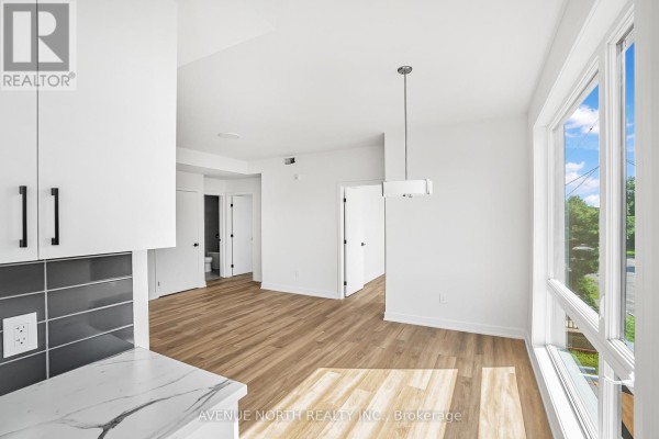 Dining area adjacent to the kitchen with large windows and light wood floors. - 03 - 391 Dieppe Street, Ottawa