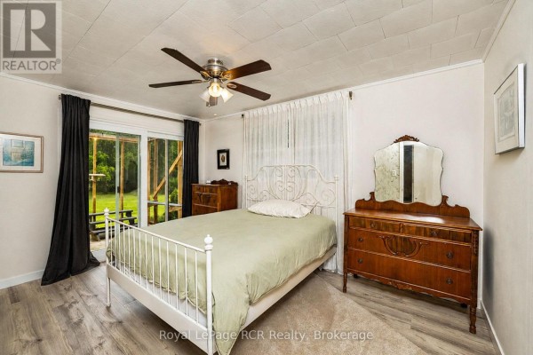 Bedroom with white metal bed, wood dresser, and sliding glass door - 046285 Old Mail Road Meaford