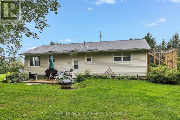 Rear exterior with deck, grill, fire pit, and wood-framed enclosure - 046285 Old Mail Road Meaford