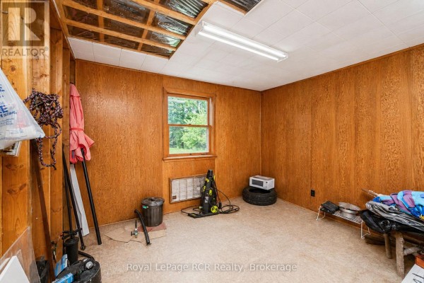 Room with wood paneling, fluorescent light, window, and storage items - 046285 Old Mail Road Meaford