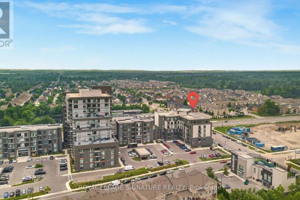 Aerial view shows a modern condominium building with a blue sky and distant treeline. - 06 - 10 Mallard Trail, Hamilton