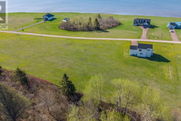 Aerial view of a residential area with houses, grassy lots, trees and a water view. - 06-24 Stacy Lane, St  Nicholas
