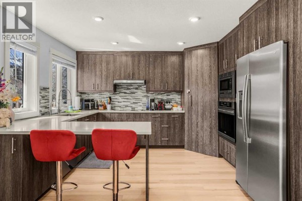 View of the kitchen with island, red bar stools, and a hallway door. - 1, 1406 2nd Avenue, Canmore
