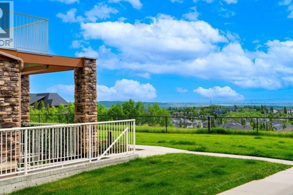 Wooden gazebo with a bench inside, surrounded by trees and a gravel path. - 1, 169 Rockyledge View Nw, Calgary
