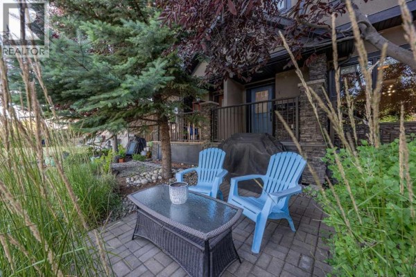 Front porch with wooden deck, stone pillar, and front door with house number. - 1, 4711 17 Avenue Nw, Calgary