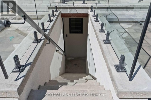 Concrete stairs lead down to a basement entrance with a glass railing and metal handrail. - 1 (bsmt) - 591 Oakwood Avenue, Toronto