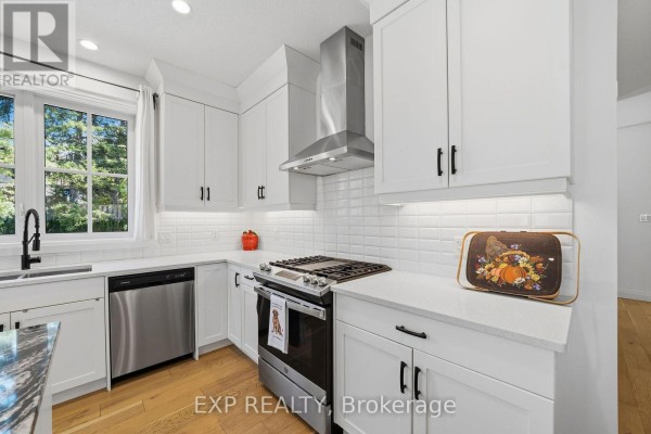 Close-up of a white kitchen with stainless steel stove, tiled backsplash, and quartz countertops. - 1 - 10038 Oxbow Drive, Middlesex Centre