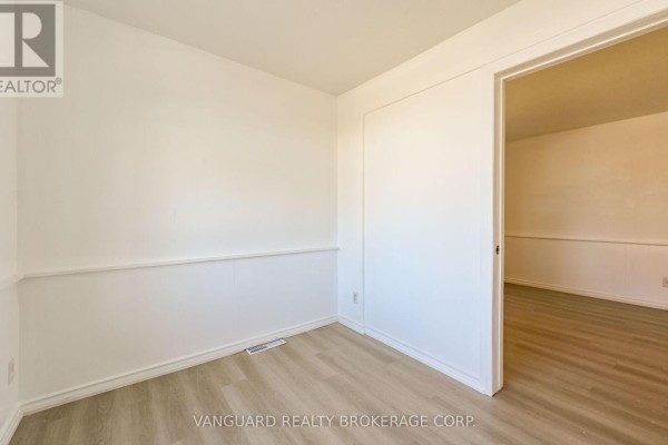Bedroom with white walls, wainscoting, and laminate flooring. - 1 - 103 Mulcaster Street, Barrie