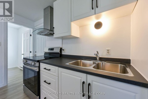 Kitchen with white cabinets, stainless steel appliances, and a double sink. - 1 - 103 Mulcaster Street, Barrie