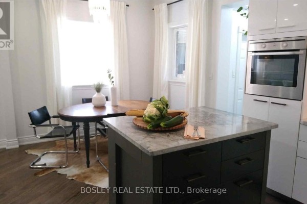 Kitchen island with granite countertop adjacent to a dining table and oven. - 1 - 11 Boustead Avenue, Toronto