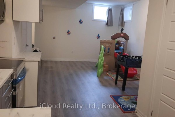 Basement room with children's play structure, foosball table, and two windows with grey curtains. - 1 - 141 Marvin Avenue, Oakville