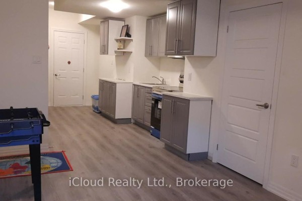 View of the kitchen area and doors, with a foosball table in the foreground. - 1 - 141 Marvin Avenue, Oakville