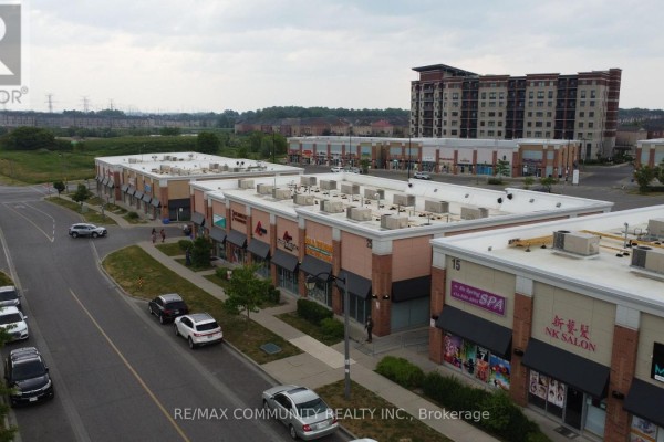 Aerial perspective of multiple commercial units with signage, parking spaces, and surrounding greenery. - 1 - 15 Karachi Drive, Markham