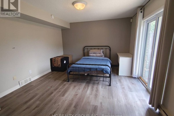 Bedroom with a single bed, metal frame, grey walls, and a sliding glass door. - 1 - 1548 Richmond Street, London North