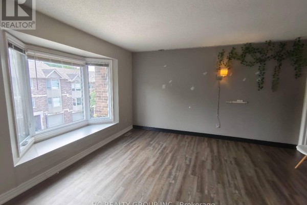 Living room with a large bay window, light grey walls, and wood-look flooring. - 1 - 1548 Richmond Street, London North