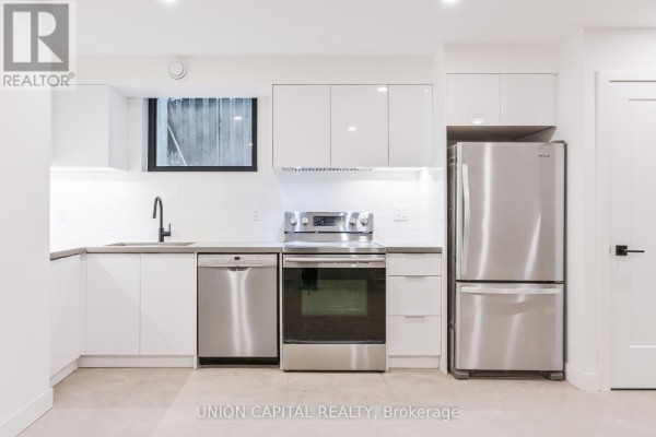 Compact white kitchen with stainless steel appliances and a black faucet. - 1 - 156 Dovercourt Road, Toronto