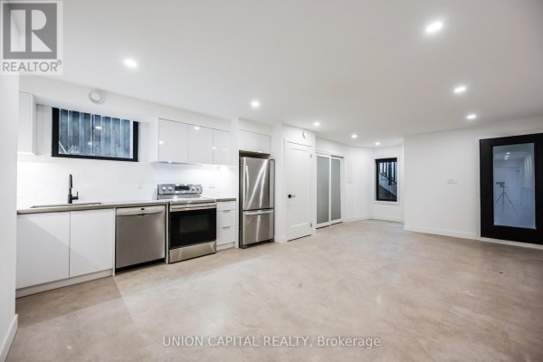 Open concept white kitchen and living area with concrete floors. - 1 - 156 Dovercourt Road, Toronto